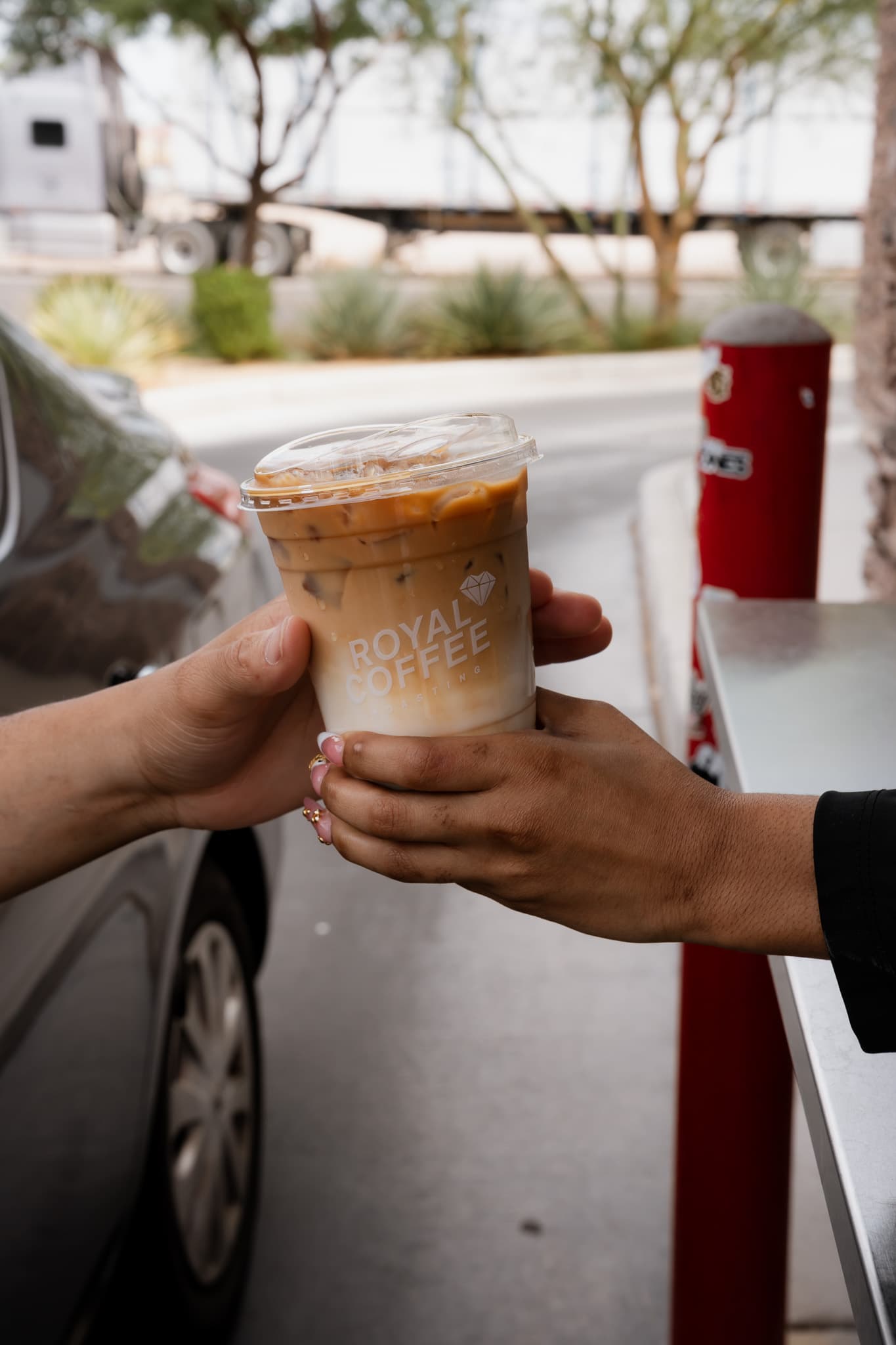 Barista handing an iced latte to a driver at the drive-thru window