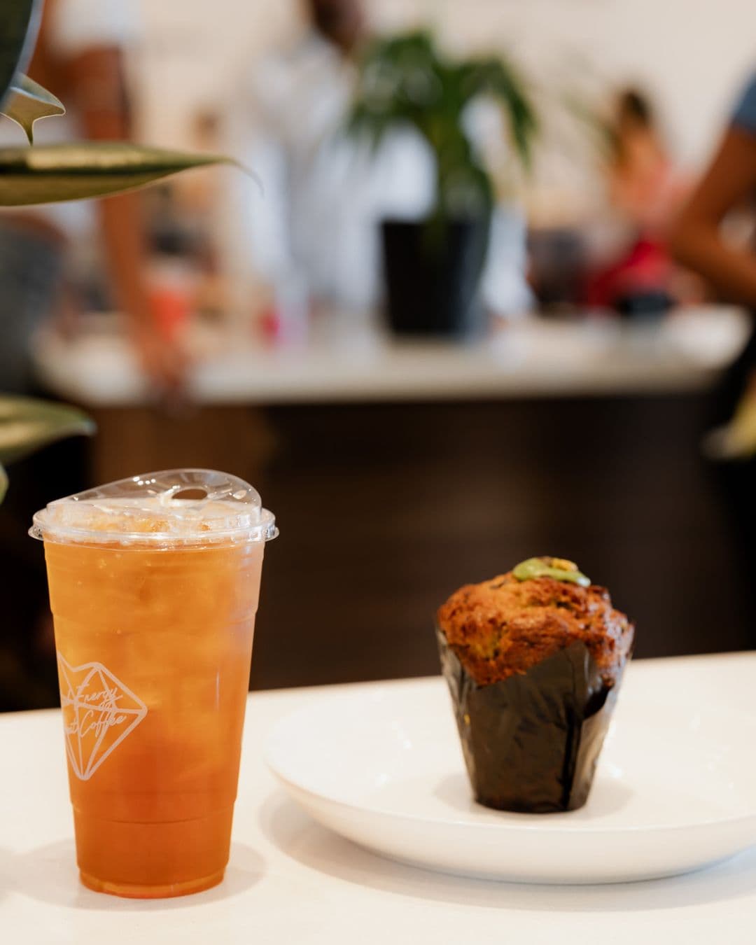 Iced tea in a Royal Coffee cup beside a pistachio muffin