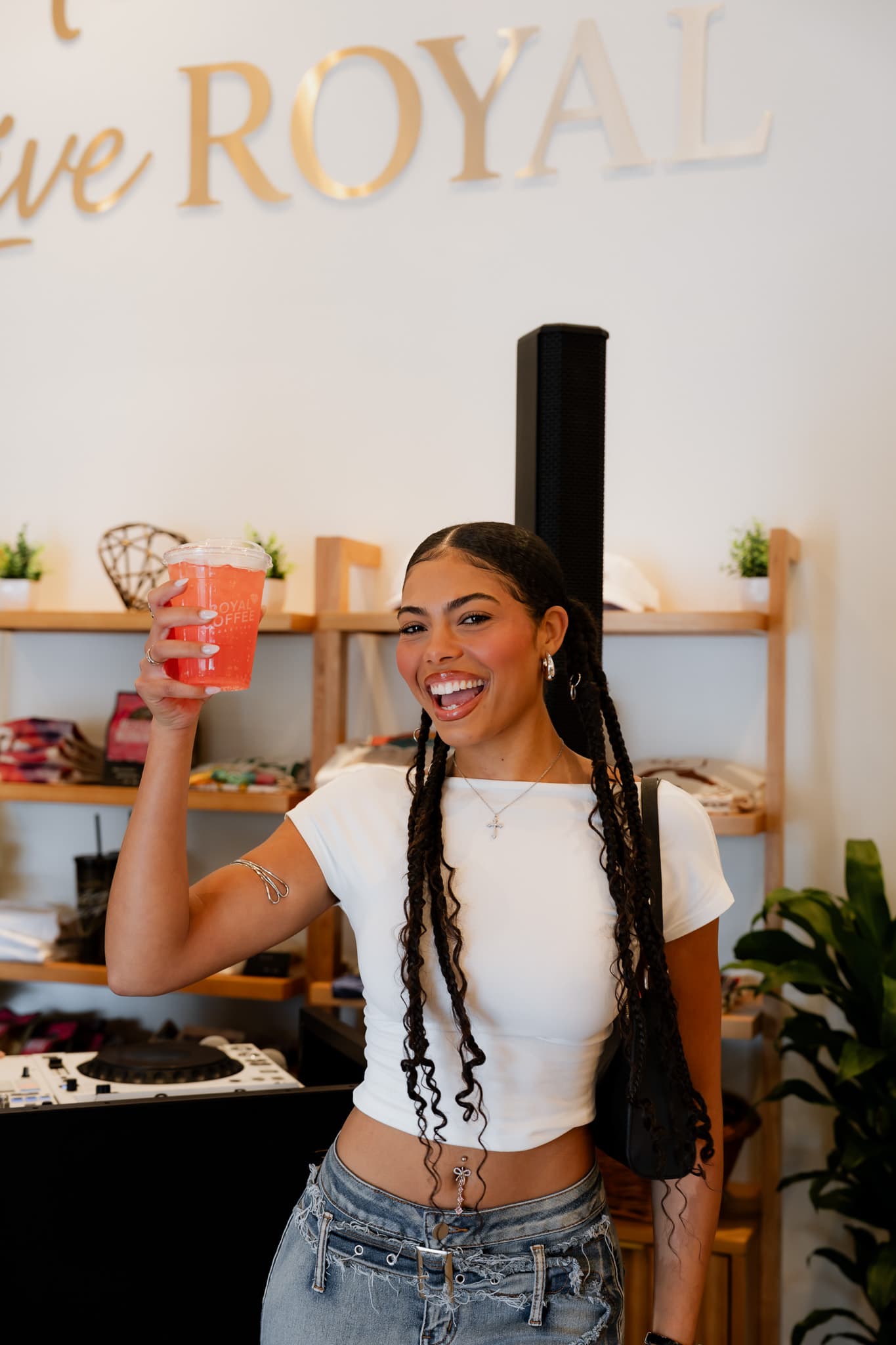 Guest smiling with a pink Royal refresher at the merch wall